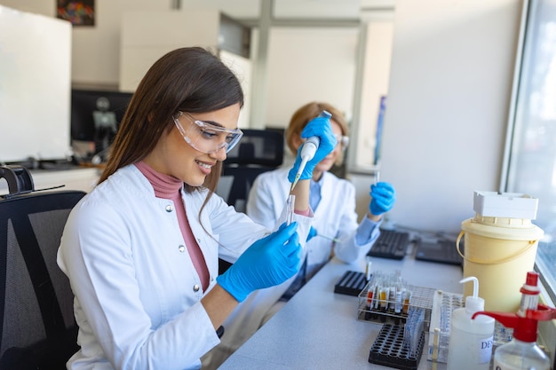 女性の医学研究科学者は、応用科学のデジタル顕微鏡で分析する前に生物学的サンプルを見て、ワクチンと薬に取り組んでいる白衣のラボエンジニア