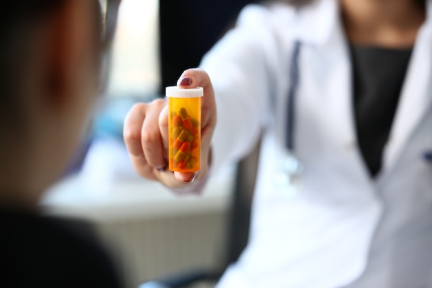 Female medicine doctor hand hold jar of pills and