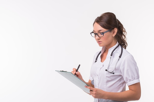 Female medicine doctor hand holding pen writing something on clipboard on white background with copy space