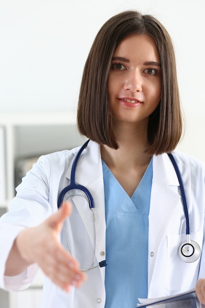 Female medicine doctor hold pad and give arm to shake