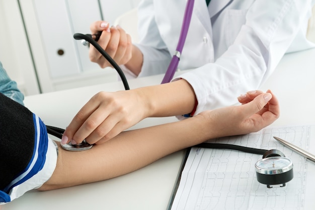 Female medicine doctor measuring blood pressure to patient. Healthcare and medical concept. Close-up ofof doctor and patient hands while pressure measuring