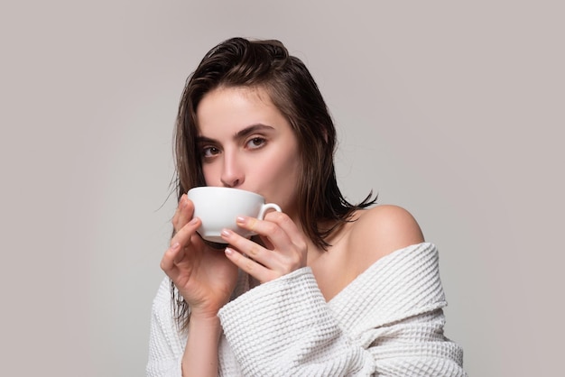 Female model in bathrobe holding cup of coffee happy smiling woman with coffee cup studio isolated