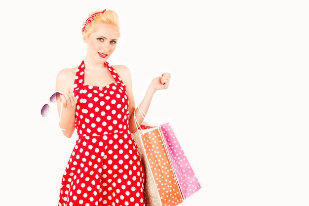 赤いドレスを着て彼女の腕に買い物袋を保持している女性モデル