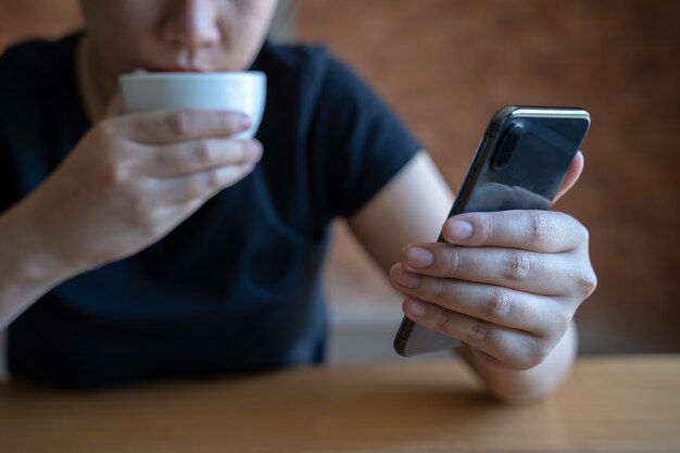 Female model holds modern smart phone   relaxing in cafe coffee