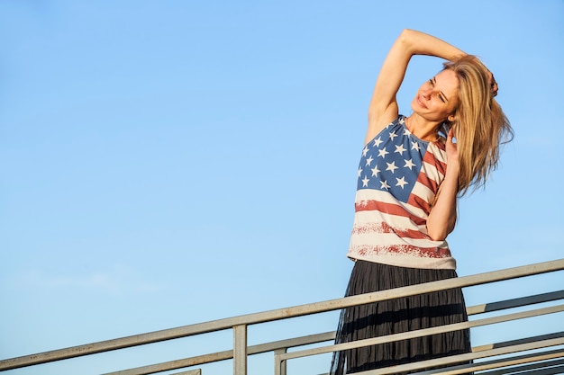Фото Женская модель на поверхности голубого неба в футболке с американским флагом