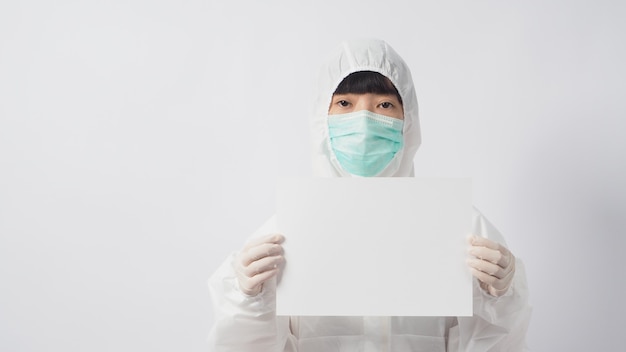 PPEとフェイスマスクと手袋をはめて手を着ている女性モデルは、白い背景の上のA4紙を保持しています。