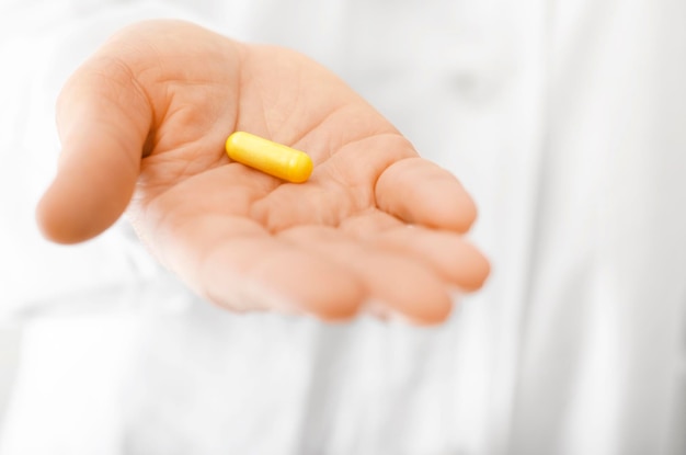 Female model in white scrub holds pill in her hand closeup view