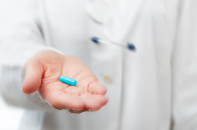 Female model in white scrub holds pill in her hand closeup view