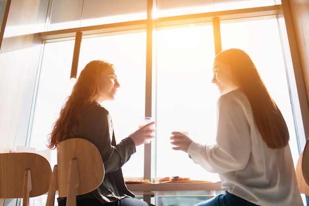 写真 女性モデルが座ってカフェで話します。昼食時にコーヒーを飲んでいる若い女性