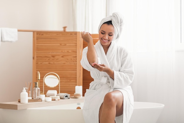 Female Moisturizing Skin Applying Moisturizer On Elbow Sitting In Bathroom