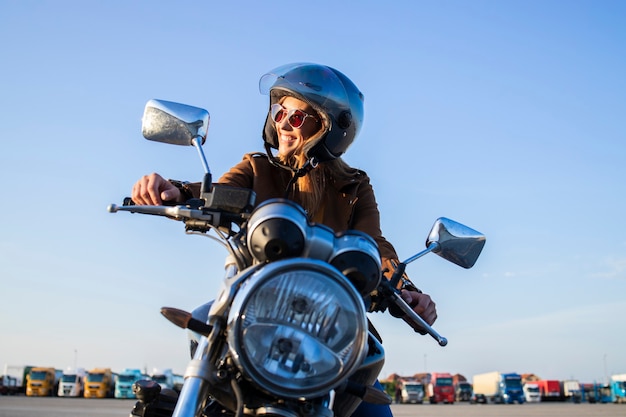 Female motorbike rider wearing helmet and riding retro style motorcycle.