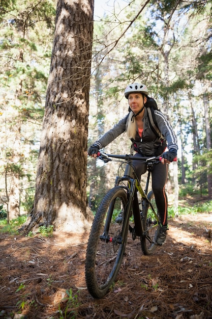 Female mountain biker riding bicycle in the forest