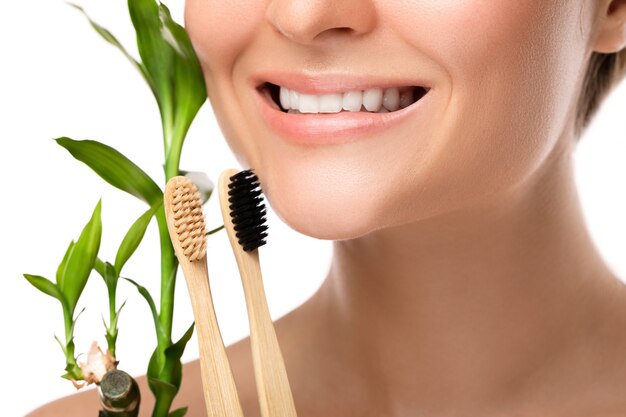 Female mouth with white teeth and bamboo toothbrush