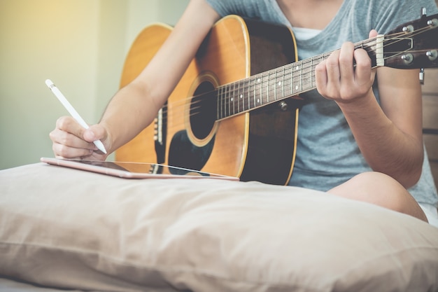 I musicisti femminili suonano la chitarra e scrivono canzoni usando il tablet.