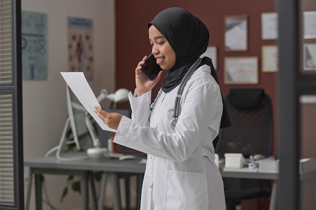 Female Muslim Doctor Having Phone Conversation in Her Office in Hospital