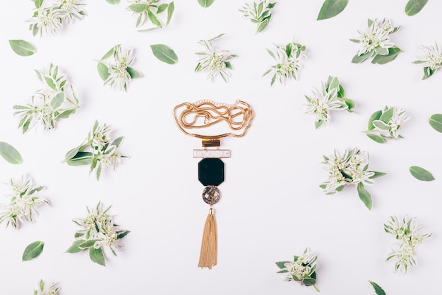 Female necklace on a white table amongst green flowers