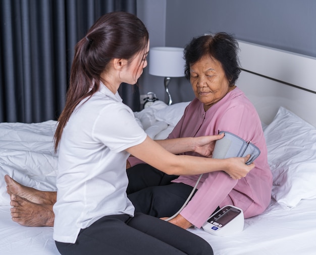 female nurse checking blood pressure of a senior woman