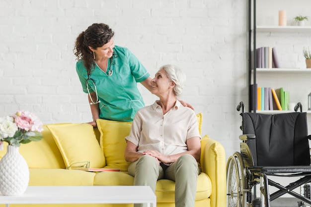 Foto infermiera femminile che consola il suo paziente senior che si siede sul sofà