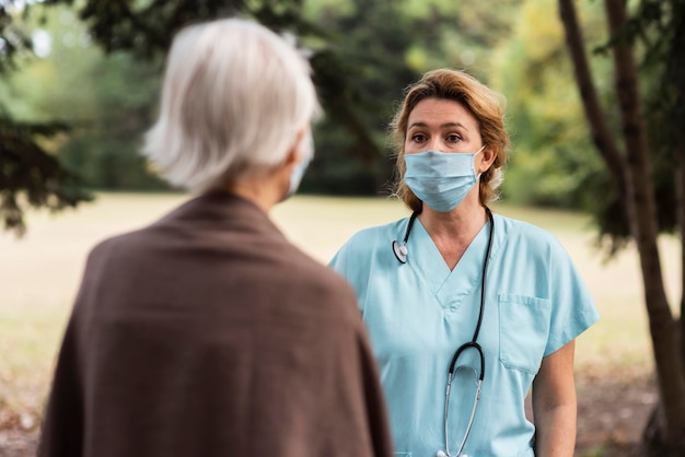 Photo female nurse conversing outdoors with elder woman