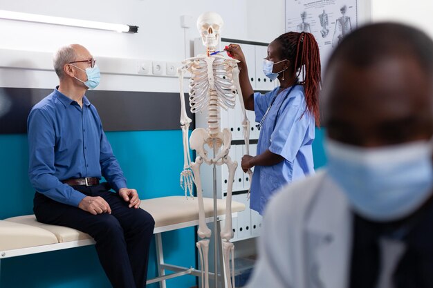 Photo female nurse showing skeleton to patient