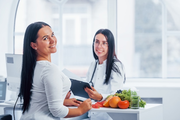 Female nutritionist gives consultation to patient indoors in the office.