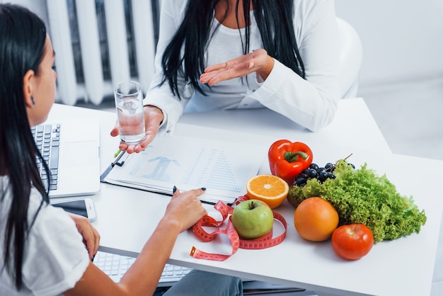 Female nutritionist gives consultation to patient indoors in the office.