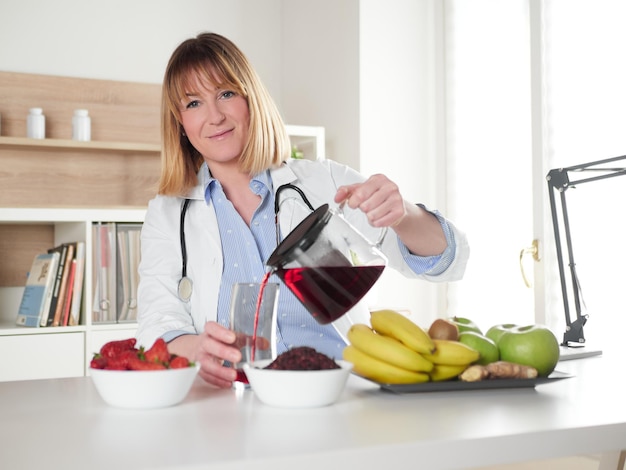 Nutrizionista femminile che versa bevanda per infusione di ibisco