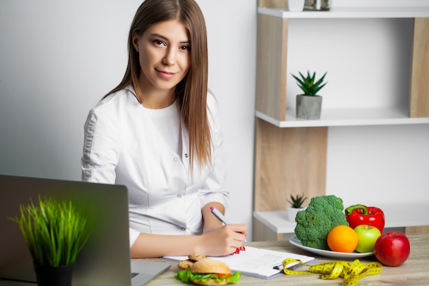 Фото Женский диетолог с фруктами, работающих на ее столе