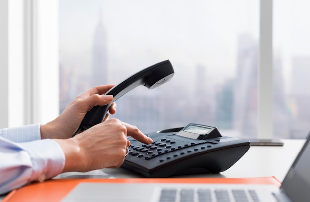 Photo female office worker working and making a phone call she is holding the receiver and dialing a number