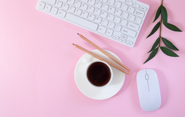 Рабочее место женского офиса с клавиатурой, компьютерной мышью, чашкой кофе и заводом на розовом фоне. Плоская планировка, вид сверху