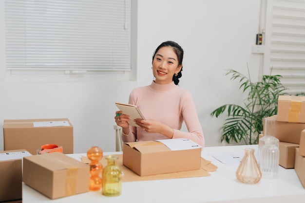 Female online store small business owner seller entrepreneur packing package post shipping box preparing delivery parcel