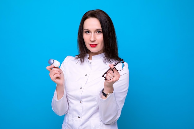 A female ophthalmologist doctor with a lens container and glasses on a blue backgroundvision check by a professional