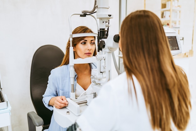 Optometrista femminile che controlla la visione del paziente presso la clinica oculistica. sanità e concetto medico.