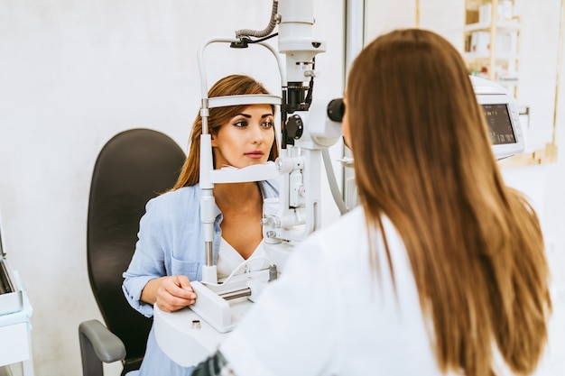 Photo female optometrist checking patient's vision at eye clinic. healthcare and medical concept.