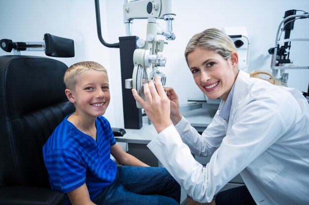 Female optometrist examining young patient on phoropter