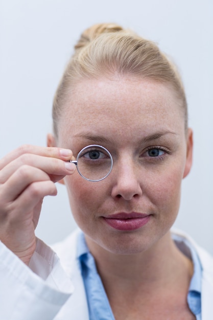 Photo female optometrist looking through magnifying glass