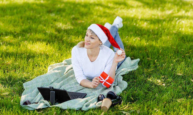 Female ordering presents on laptop and drinking coffee. Happy woman buying Christmas gifts online. Girl makes shopping online on computer. Surfing and shopping. Merry Christmas and Happy New Year