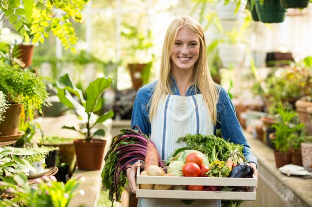 Female owner holding fresh vegetables in crate