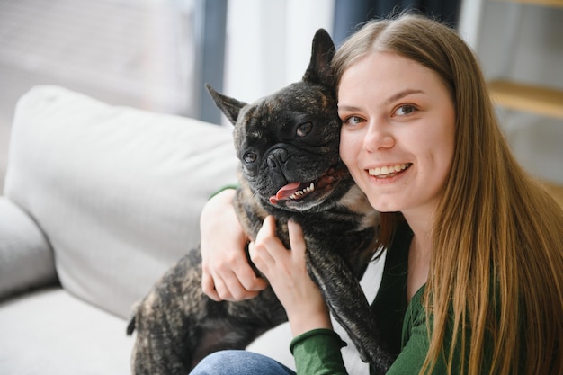 Proprietario femminile che gioca con un cane gioioso a casa giocando con il concetto di cane