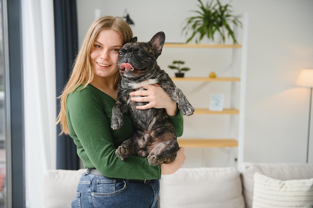 Proprietario femminile che gioca con un cane gioioso a casa giocando con il concetto di cane