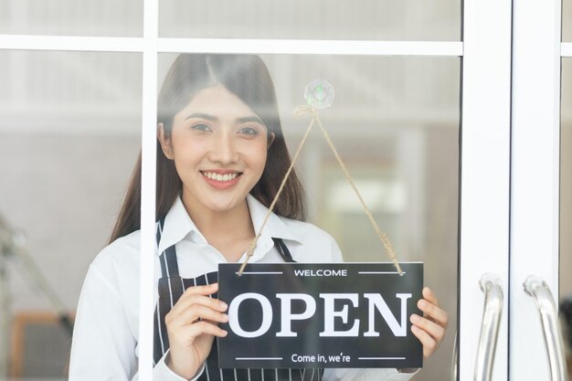 Female owner turning sign board to open coffee shop smile and happiness Smiling asian woman open food and beverage cafe ready to service after quarantine due to virus pandemic Small business