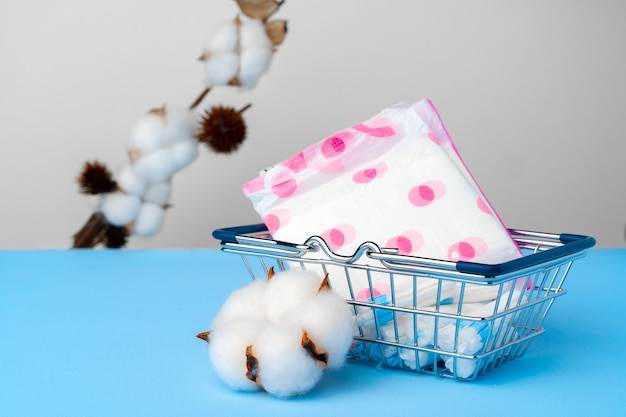 Female pads and tampons on blue paper surface