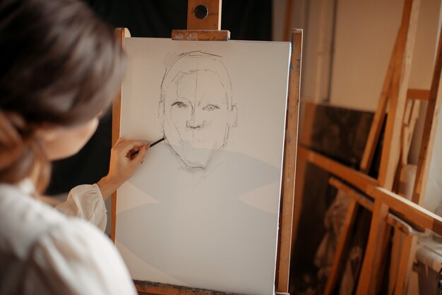 Female painter in studio, pencil sketch on easel