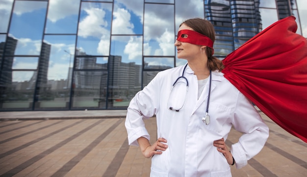 Female paramedic in a superhero raincoat standing on a city street