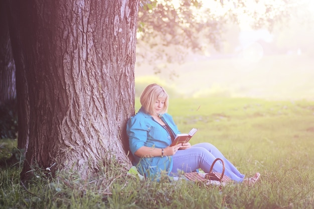 Женщина в парке на закате с книгой