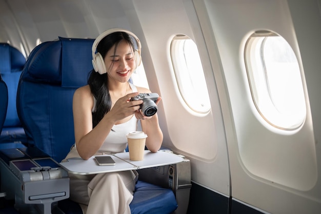 女性の乗客が夏休みの飛行中にカメラで写真をチェックしている