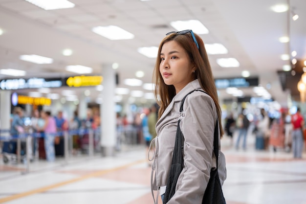 A female passenger is looking for her checkin counter walking in the airport with her bags