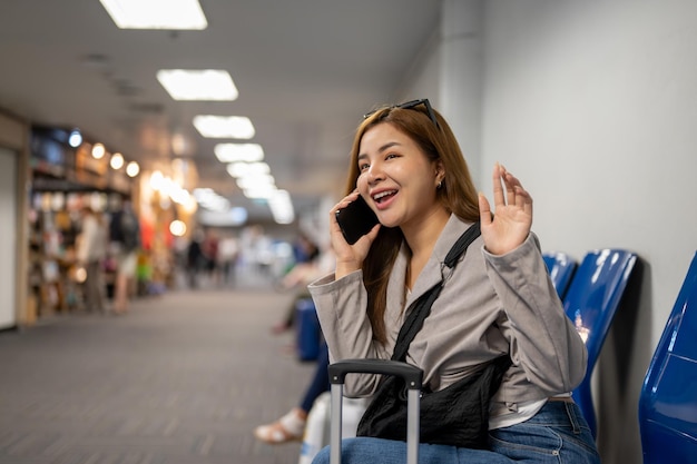 A female passenger is talking on the phone while sitting at a waiting seat in the airport terminal