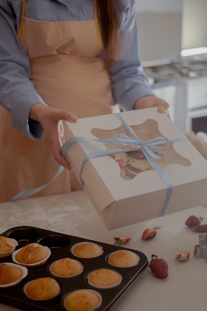 Photo a female pastry chef packs cupcakes into packaging for shipping to customers showcasing homemade