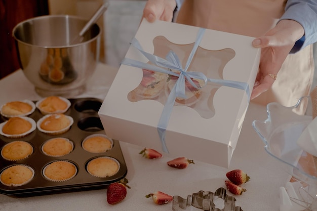 A female pastry chef packs cupcakes into packaging for shipping to customers showcasing homemade